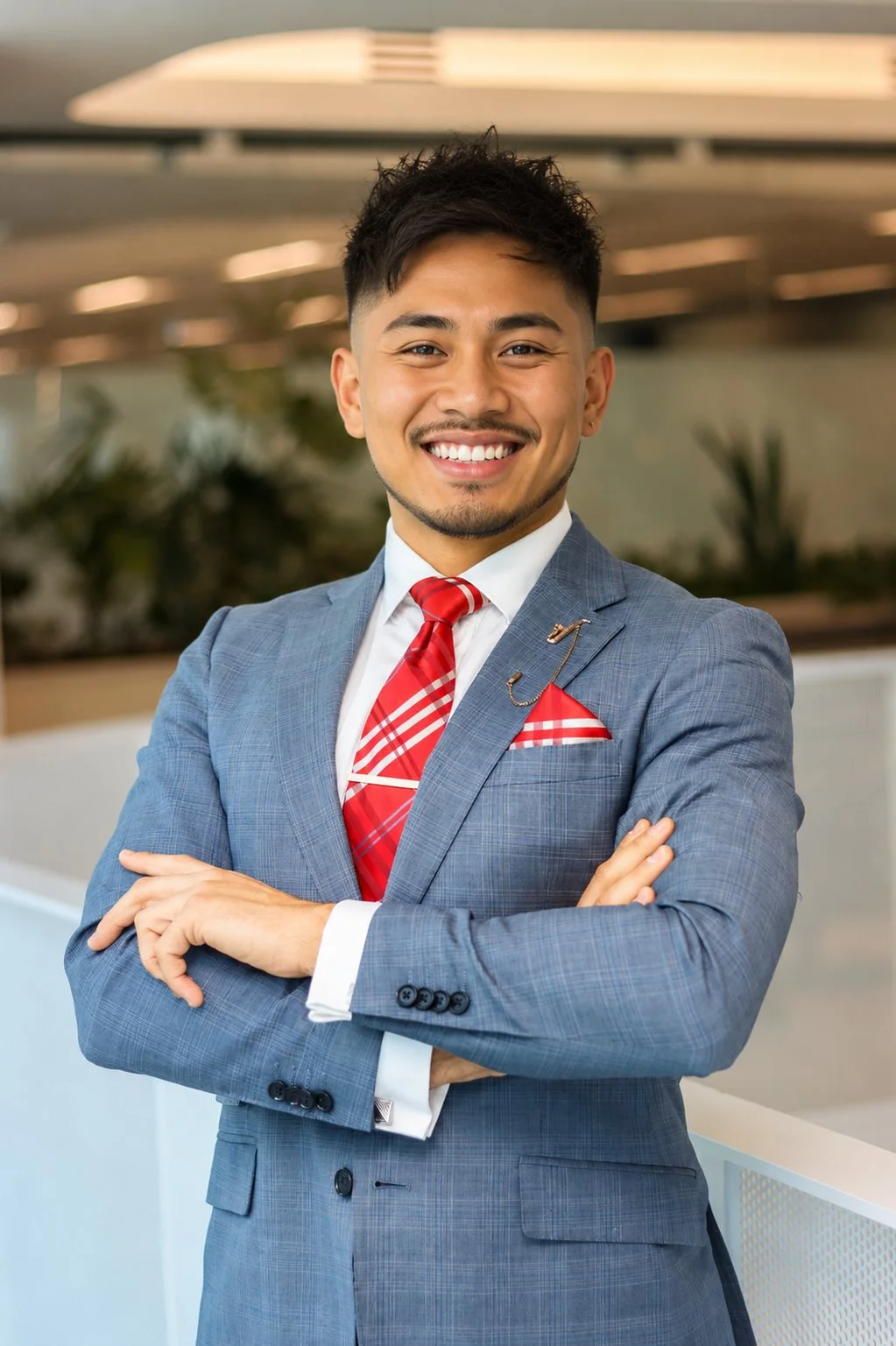 Professional portrait of a man in a grey suit and red tie.