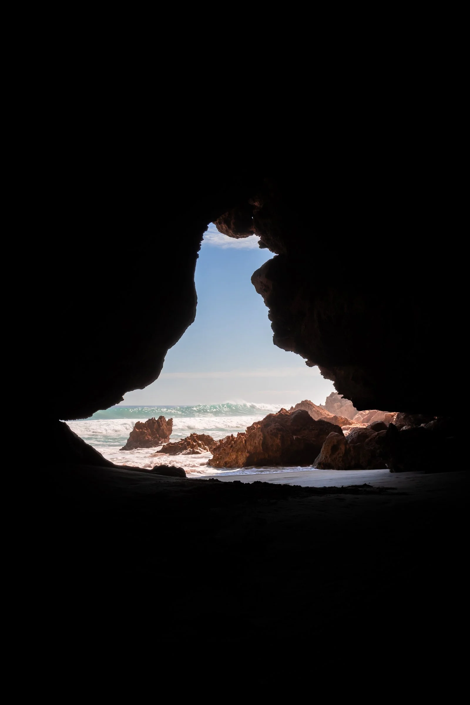 Ocean light is framed by the dark opening of a coastal cave on Kangaroo Island.